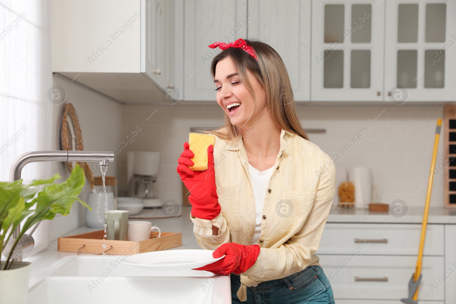 Photo of Woman singing while washing dishes in kitchen