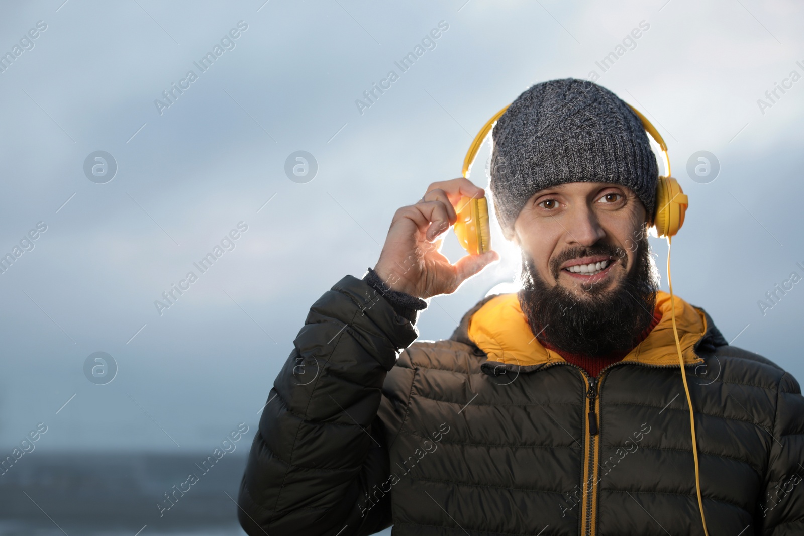 Photo of Mature man with headphones listening to music outdoors, space for text