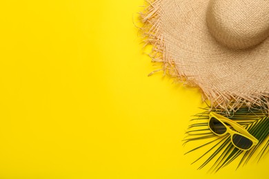 Photo of Straw hat, sunglasses, palm leaf and space for text on yellow background, flat lay. Stylish headdress