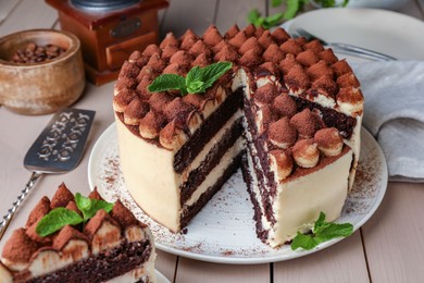 Delicious tiramisu cake with mint leaves on wooden table