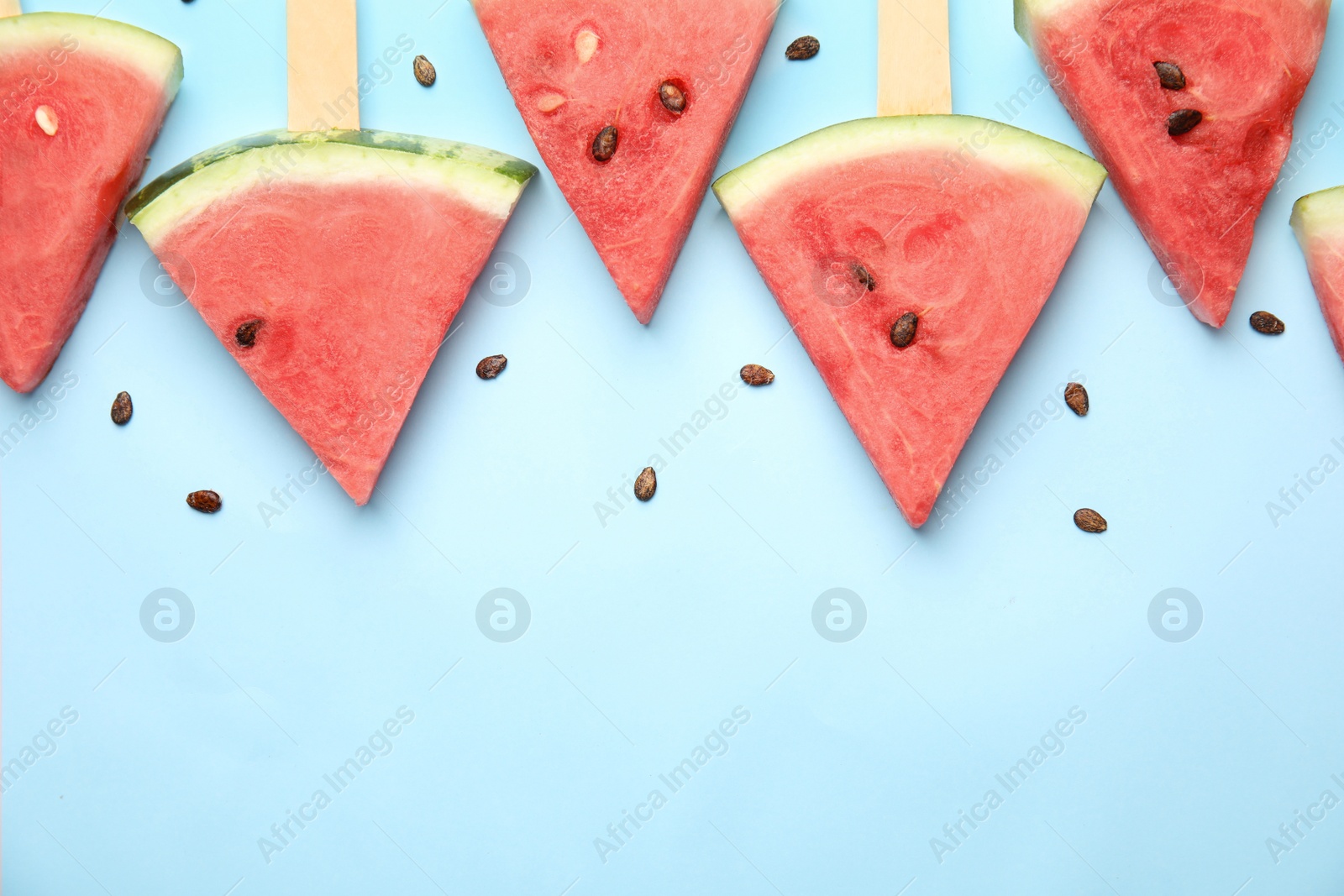 Photo of Slices of ripe watermelon on light blue background, flat lay. Space for text