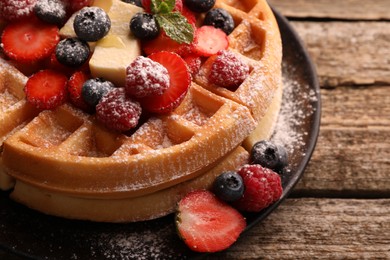 Photo of Tasty Belgian waffles with fresh berries, cheese and powdered sugar on wooden table, closeup