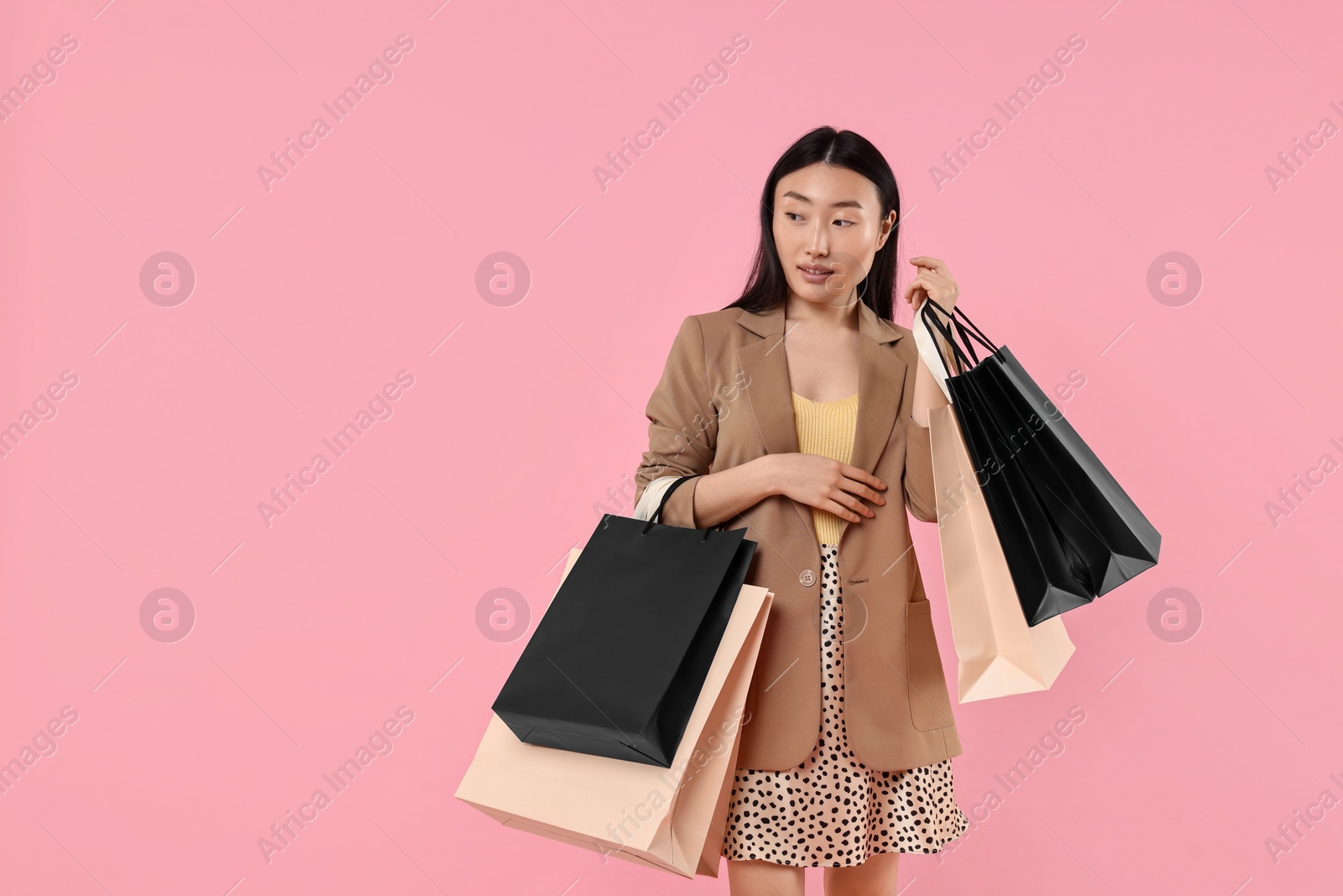 Photo of Beautiful woman with shopping bags on pink background. Space for text