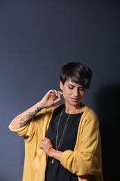 Photo of Trendy young woman with tattoo on grey background