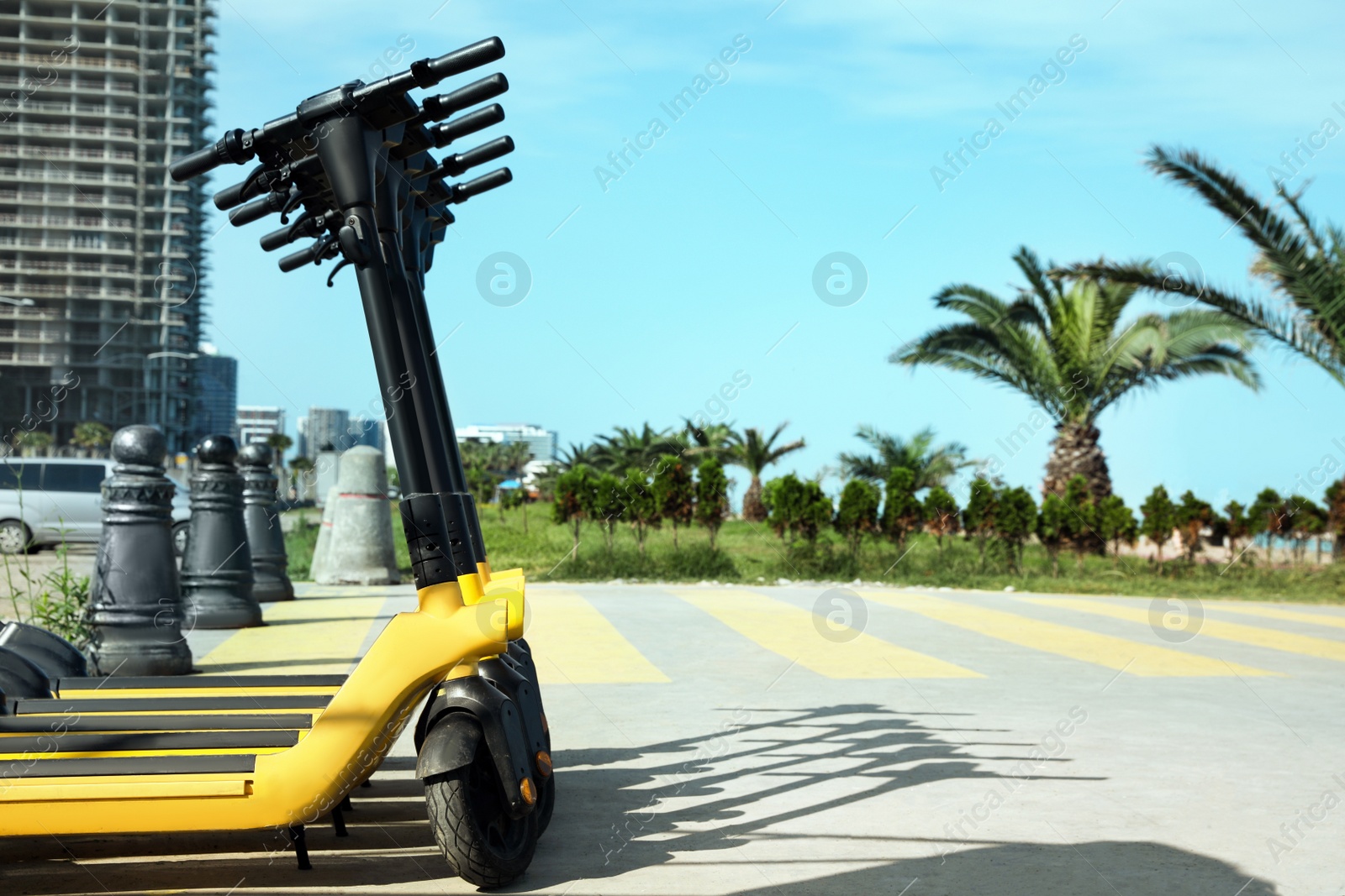 Photo of Many modern electric scooters on city street, space for text. Rental service