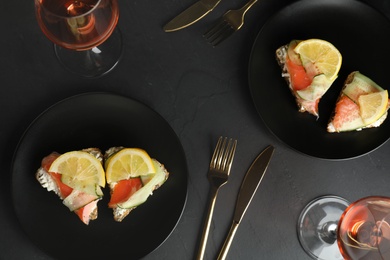 Photo of Flat lay composition with delicious bruschettas with salmon on black table