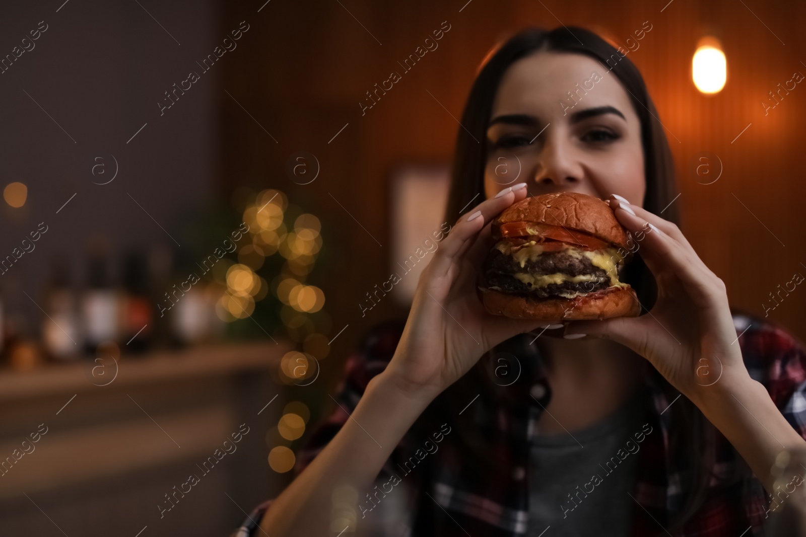 Photo of Young woman eating tasty burger in cafe