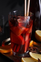 Photo of Glass of aromatic punch drink and ingredients on table, closeup