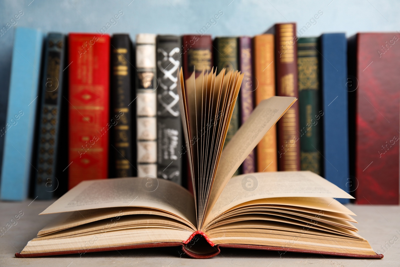 Photo of Open old book on light table in front of others