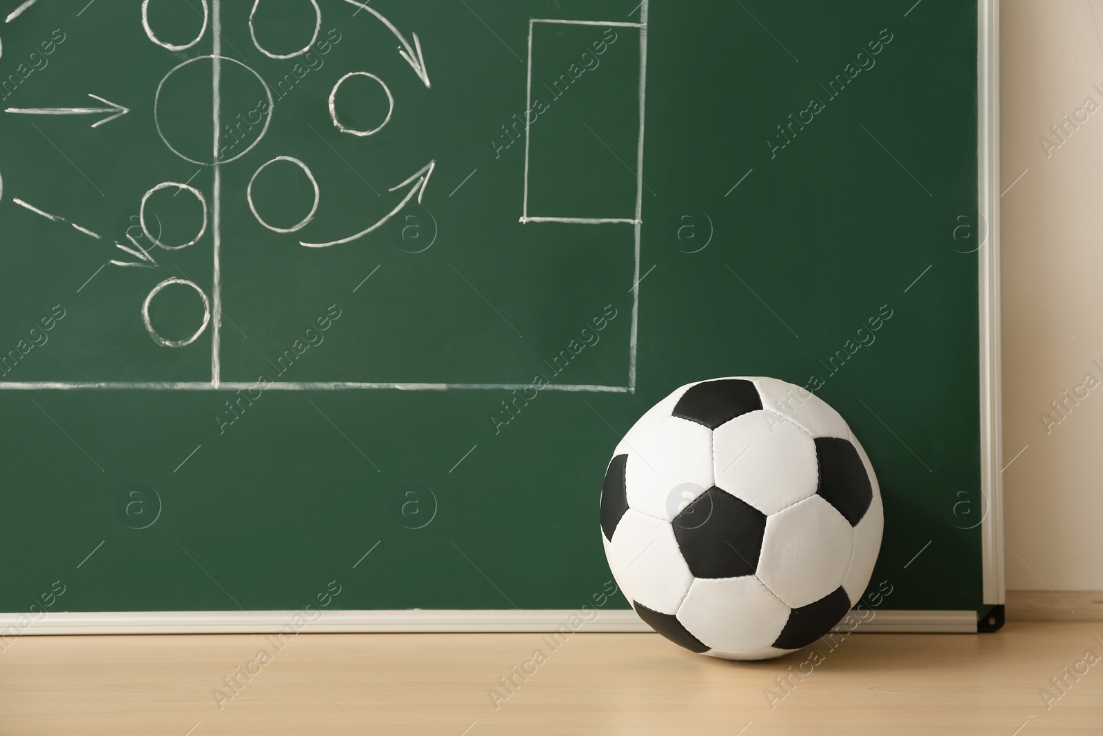 Photo of Soccer ball near chalkboard with football game scheme on table