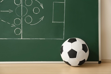 Soccer ball near chalkboard with football game scheme on table