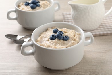 Photo of Tasty oatmeal porridge with blueberries in bowl served on wooden table