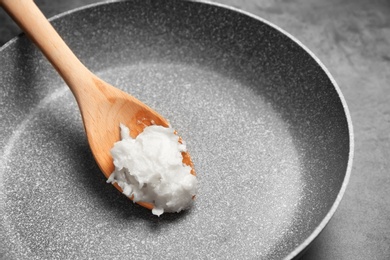 Photo of Frying pan with coconut oil on grey background, closeup