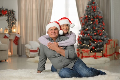 Happy mature couple in Santa hats at home. Christmas celebration