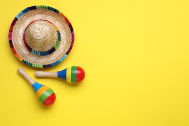 Photo of Colorful maracas and sombrero hat on yellow background, flat lay with space for text. Musical instrument