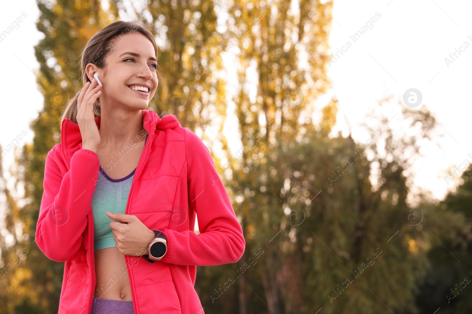 Photo of Young woman with wireless headphones listening to music outdoors. Space for text