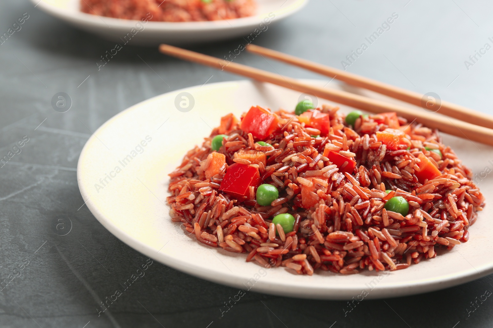 Photo of Tasty brown rice with vegetables on table, closeup