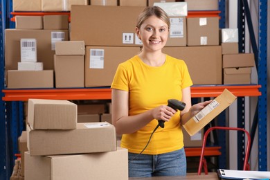 Photo of Post office worker with scanner reading parcel barcode indoors