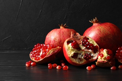 Photo of Ripe pomegranates on table against dark background. Space for text