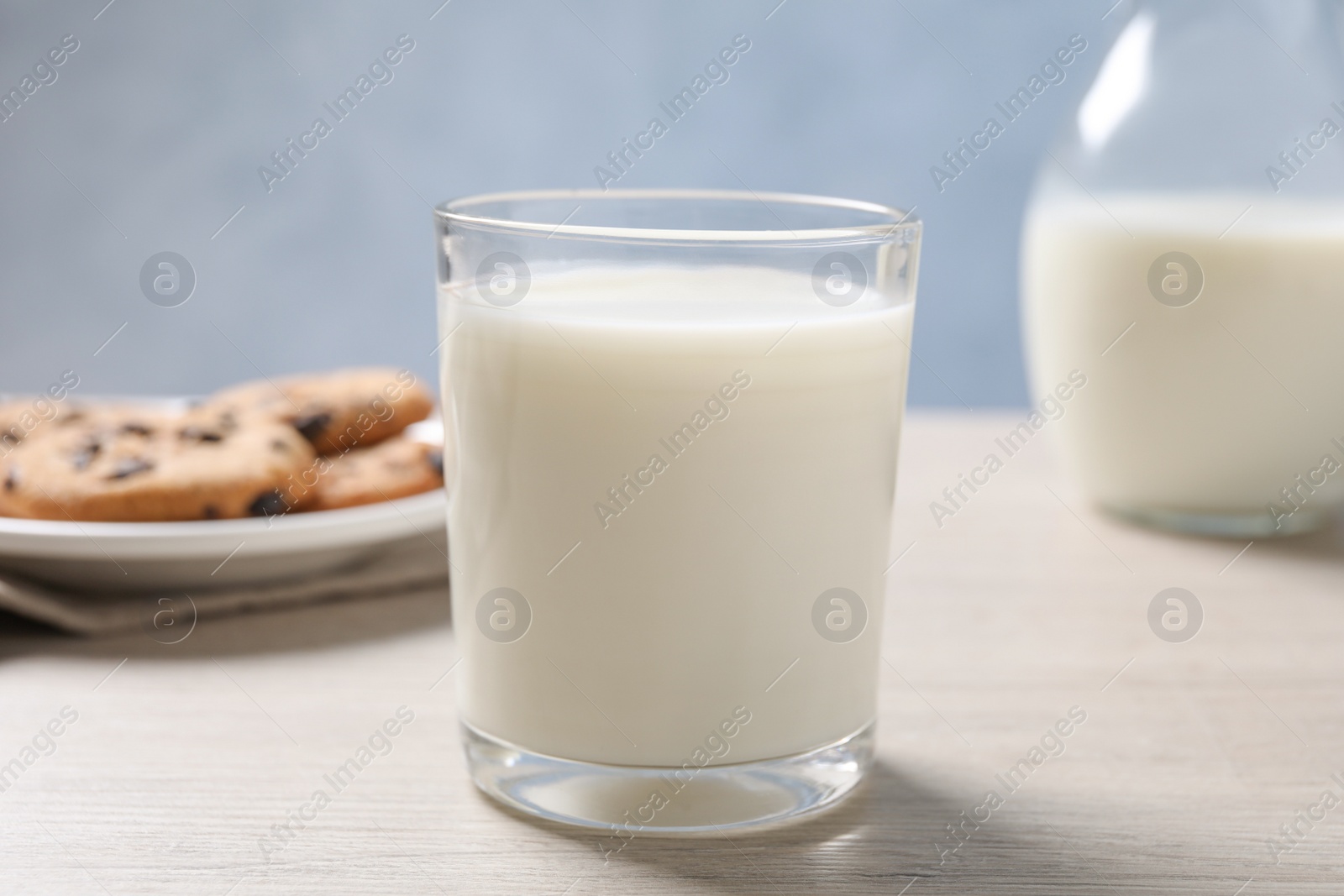 Photo of Glass of fresh milk near cookies on white table