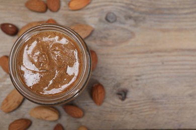 Photo of Tasty almond nut paste in jar on wooden table, top view. Space for text