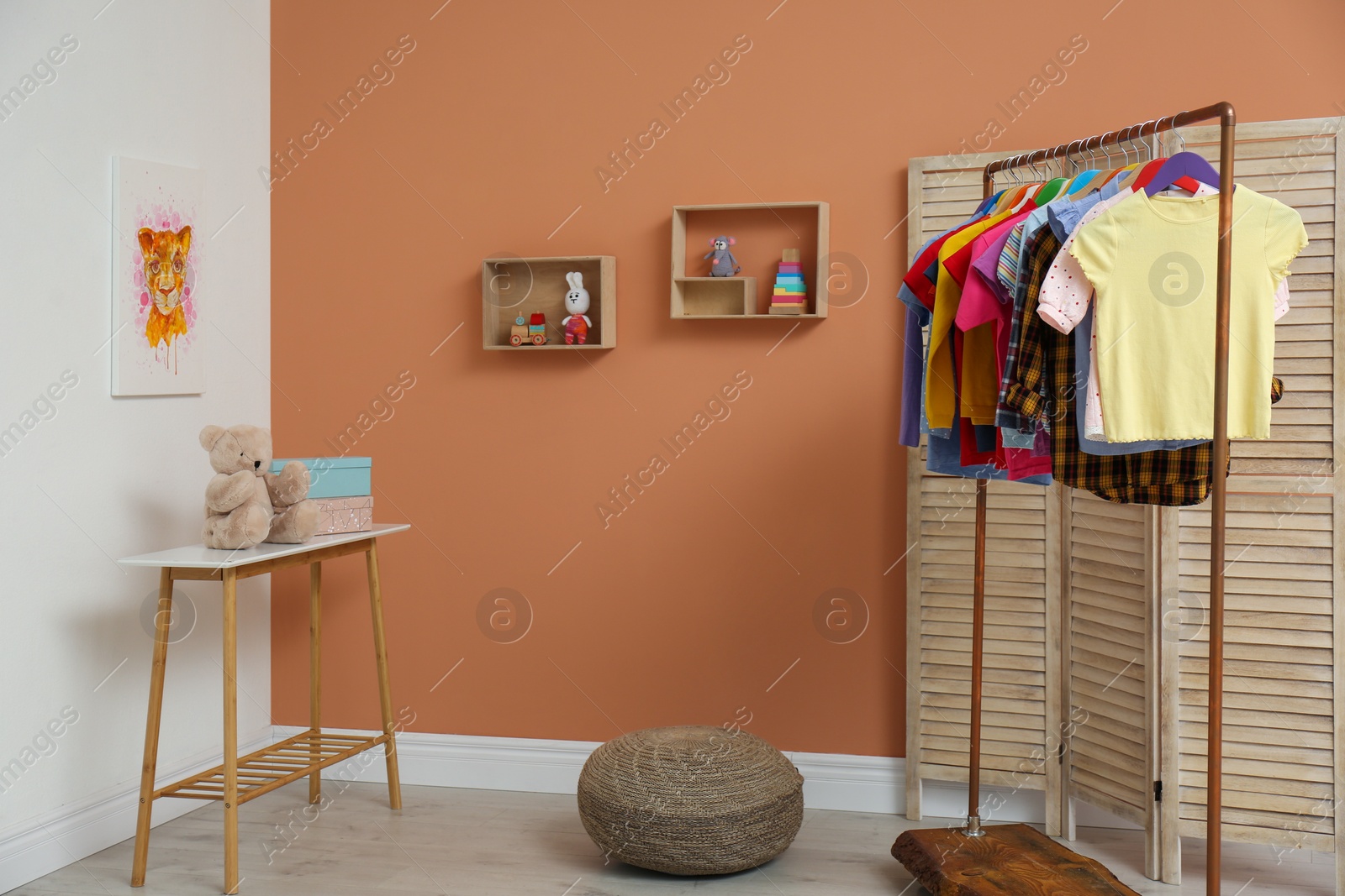 Photo of Different child's clothes hanging on rack in room