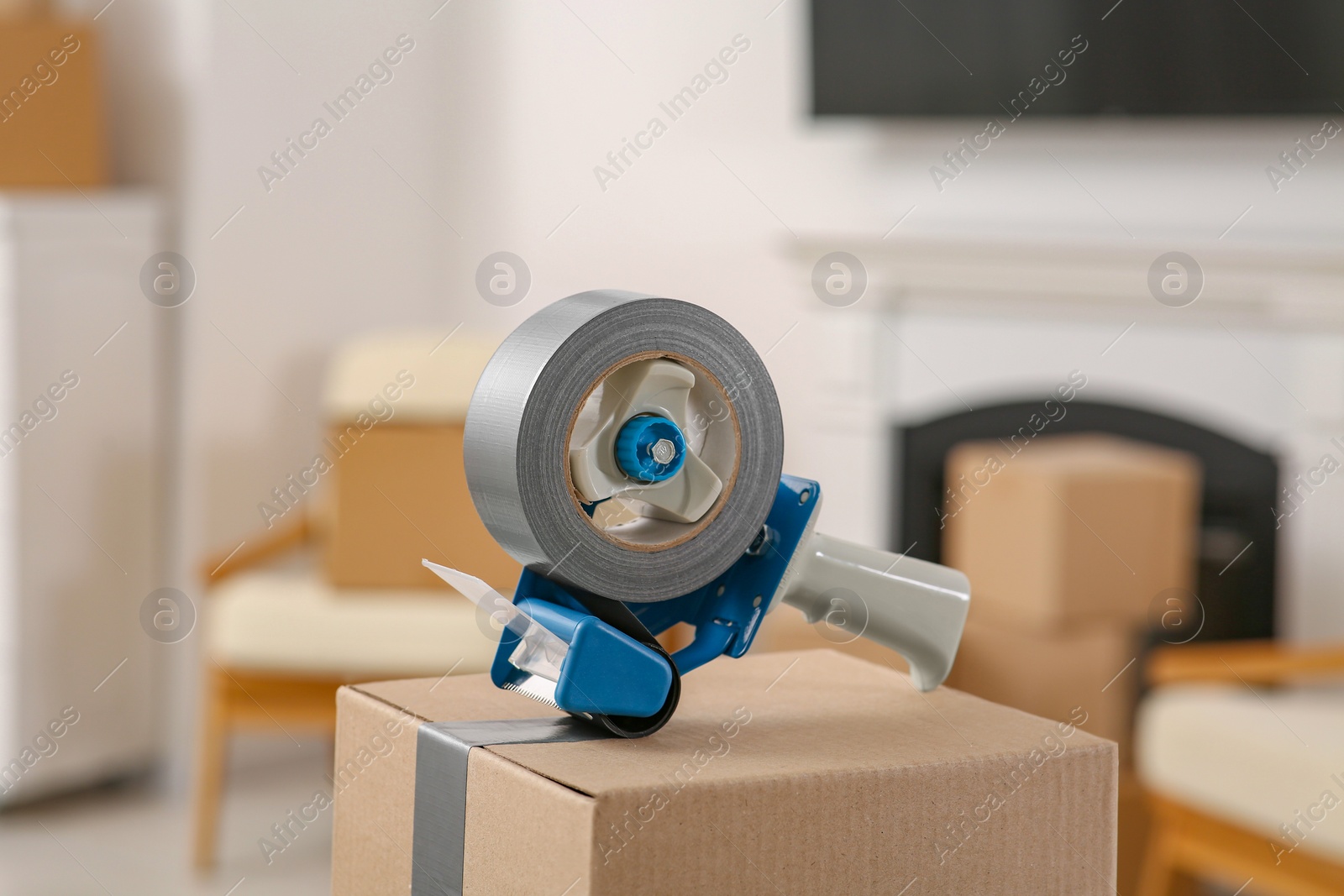 Photo of Dispenser with roll of adhesive tape on box indoors