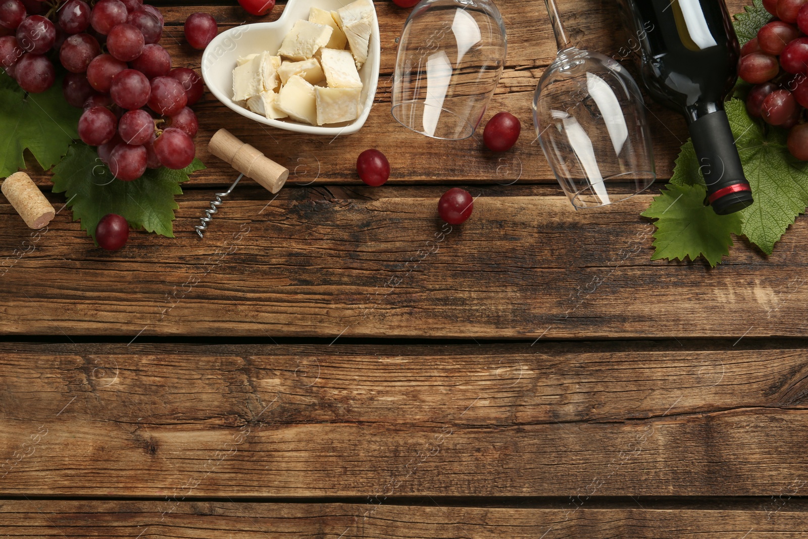 Photo of Tasty red wine and snacks on wooden table, flat lay. Space for text