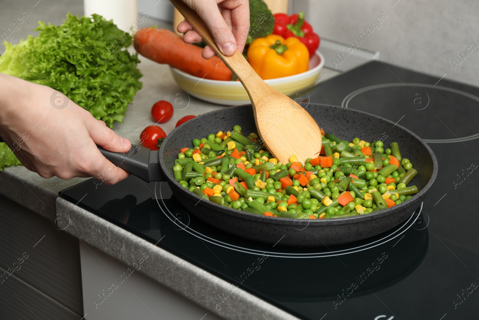 Photo of Woman cooking tasty vegetable mix in frying pan at home, closeup