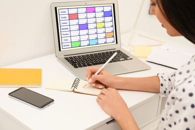 Photo of Woman planning her schedule with calendar app on laptop in office, closeup