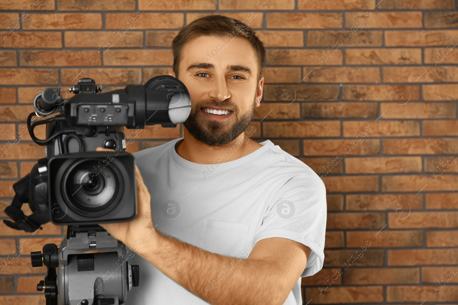 Photo of Operator with professional video camera near brick wall