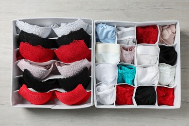 Photo of Organizers with folded women's underwear on light wooden table, flat lay