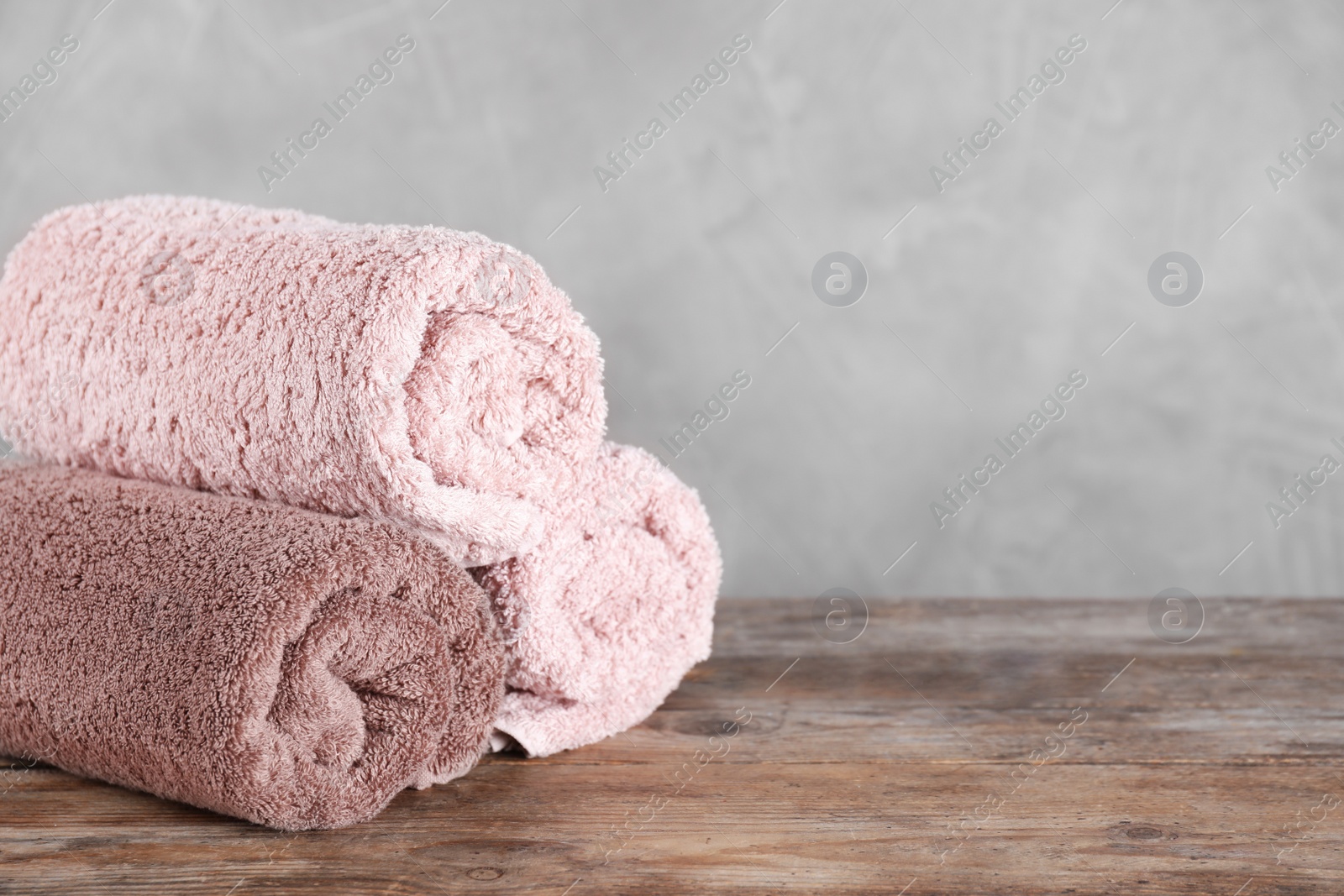 Photo of Rolled bath towels on wooden table. Space for text