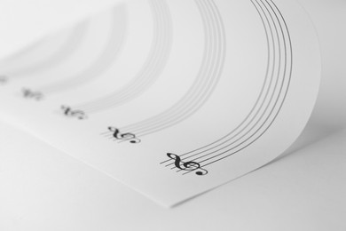 Sheet with empty staves for music notes and treble clef on white background, closeup