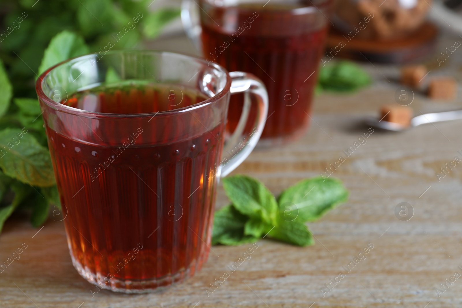 Photo of Cup with hot aromatic mint tea on wooden table, closeup. Space for text