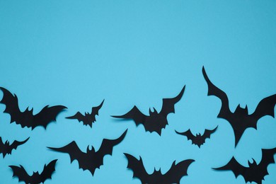 Photo of Flat lay composition with paper bats on light blue background, space for text. Halloween decor