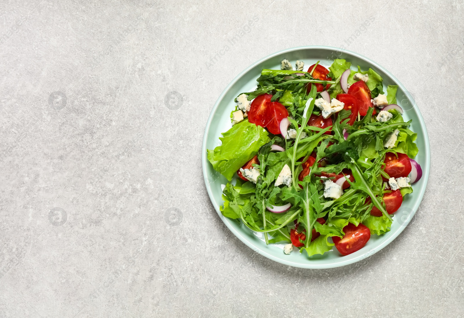 Photo of Delicious salad with arugula and tomatoes on grey table, top view. Space for text