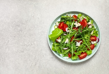 Delicious salad with arugula and tomatoes on grey table, top view. Space for text