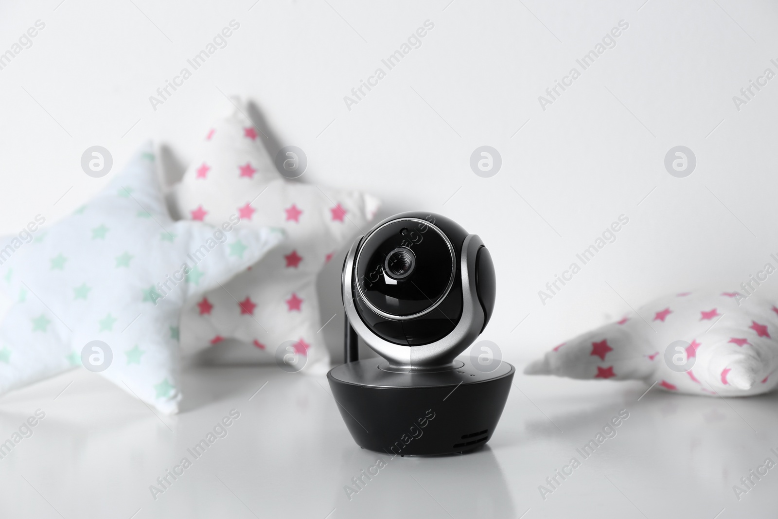 Photo of Modern CCTV security camera and decorative nursery pillows on table