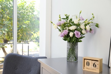 Photo of Bouquet of beautiful Eustoma flowers on chest of drawers in room. Space for text
