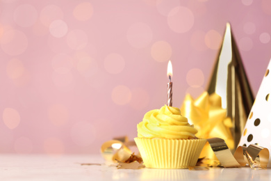 Photo of Delicious birthday cupcake with cream and burning candle on white table. Space for text