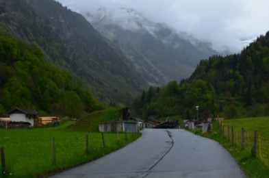 Blurred view of empty asphalt road and buildings in mountains