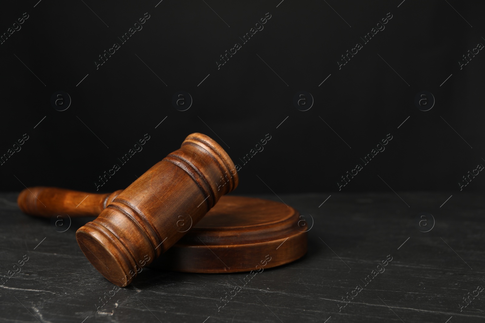 Photo of Wooden gavel on dark textured table, closeup. Space for text