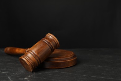 Photo of Wooden gavel on dark textured table, closeup. Space for text