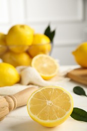 Photo of Wooden citrus reamer and fresh lemons on white table, closeup