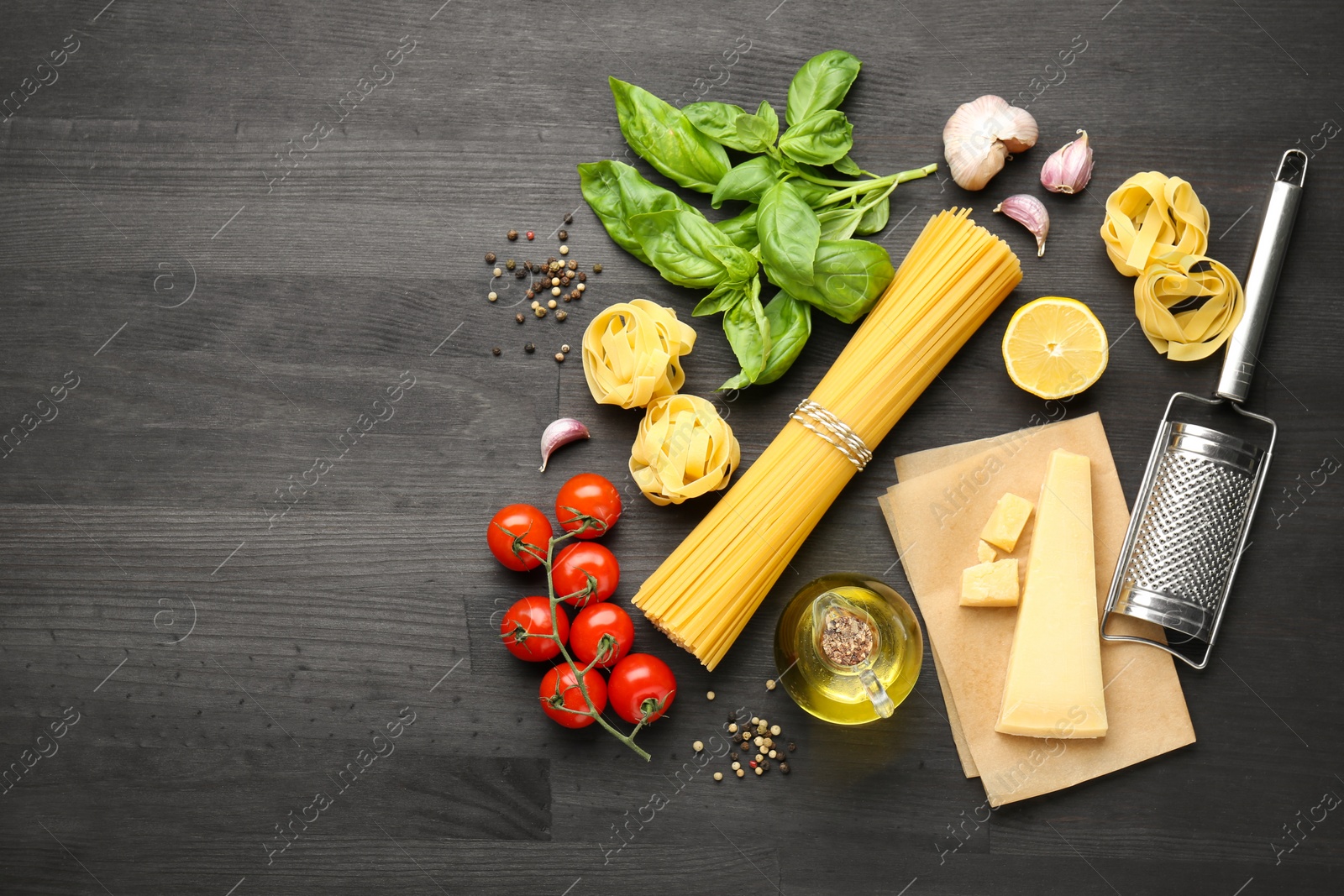 Photo of Different types of pasta, products, peppercorns and garter on dark wooden table, flat lay. Space for text