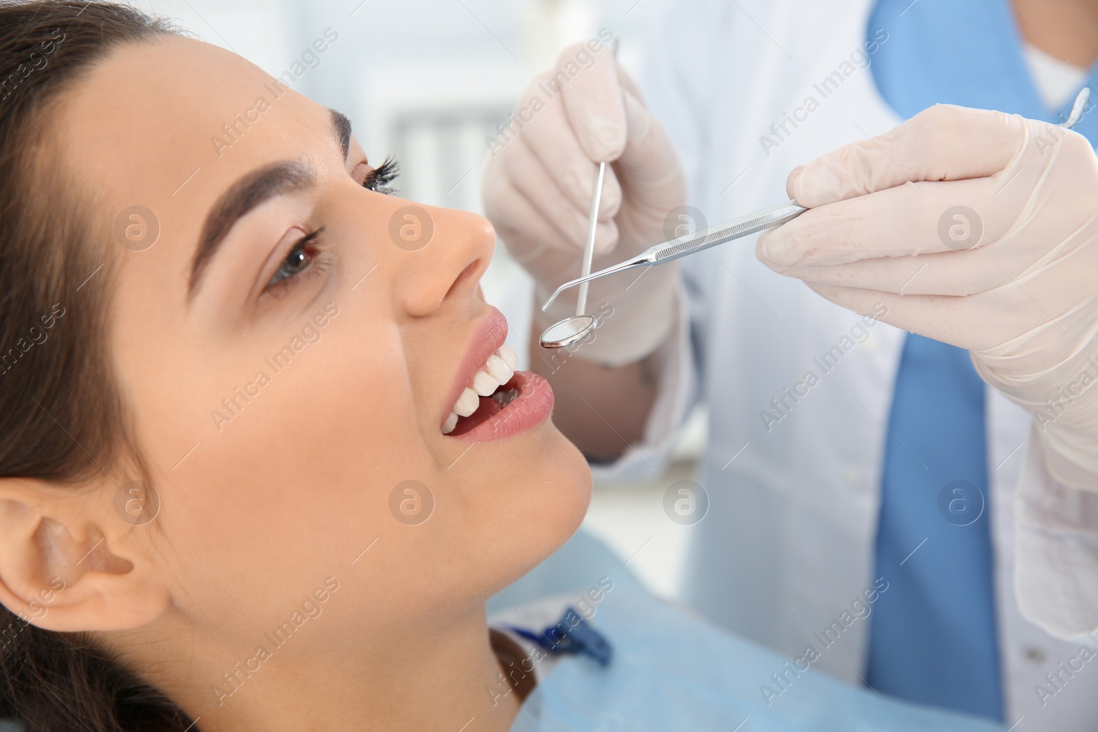 Photo of Dentist examining patient's teeth in modern clinic