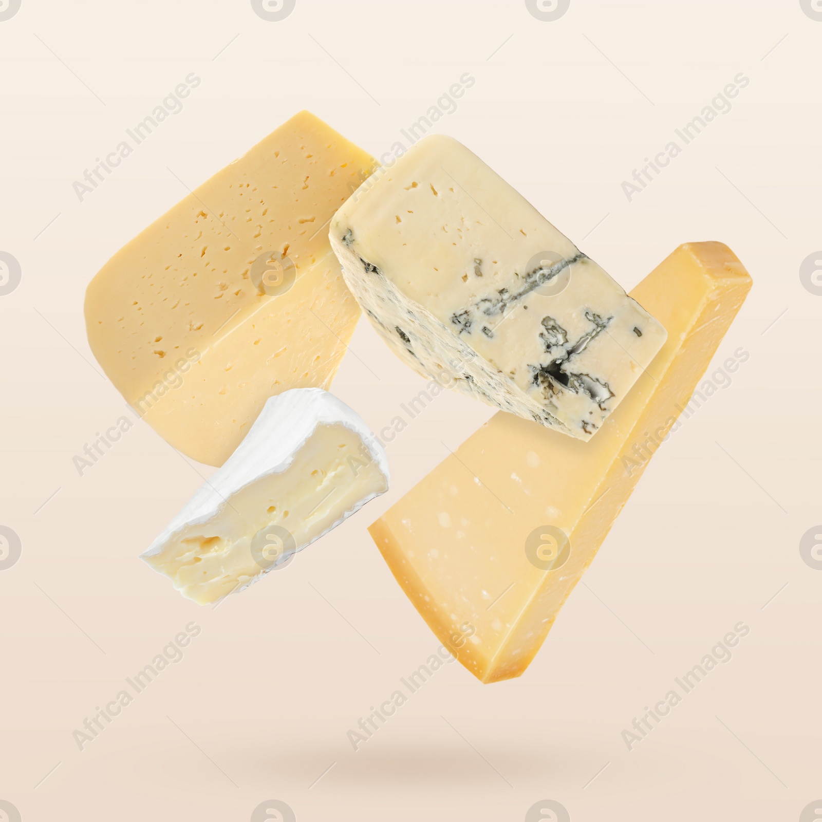 Image of Different kinds of cheese falling on beige background