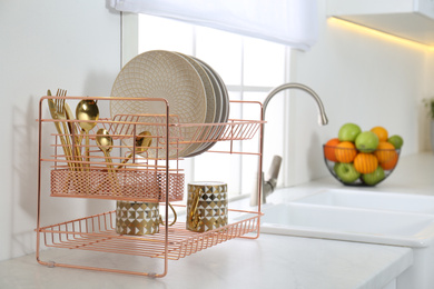 Photo of Clean dishes on drying rack in modern kitchen interior