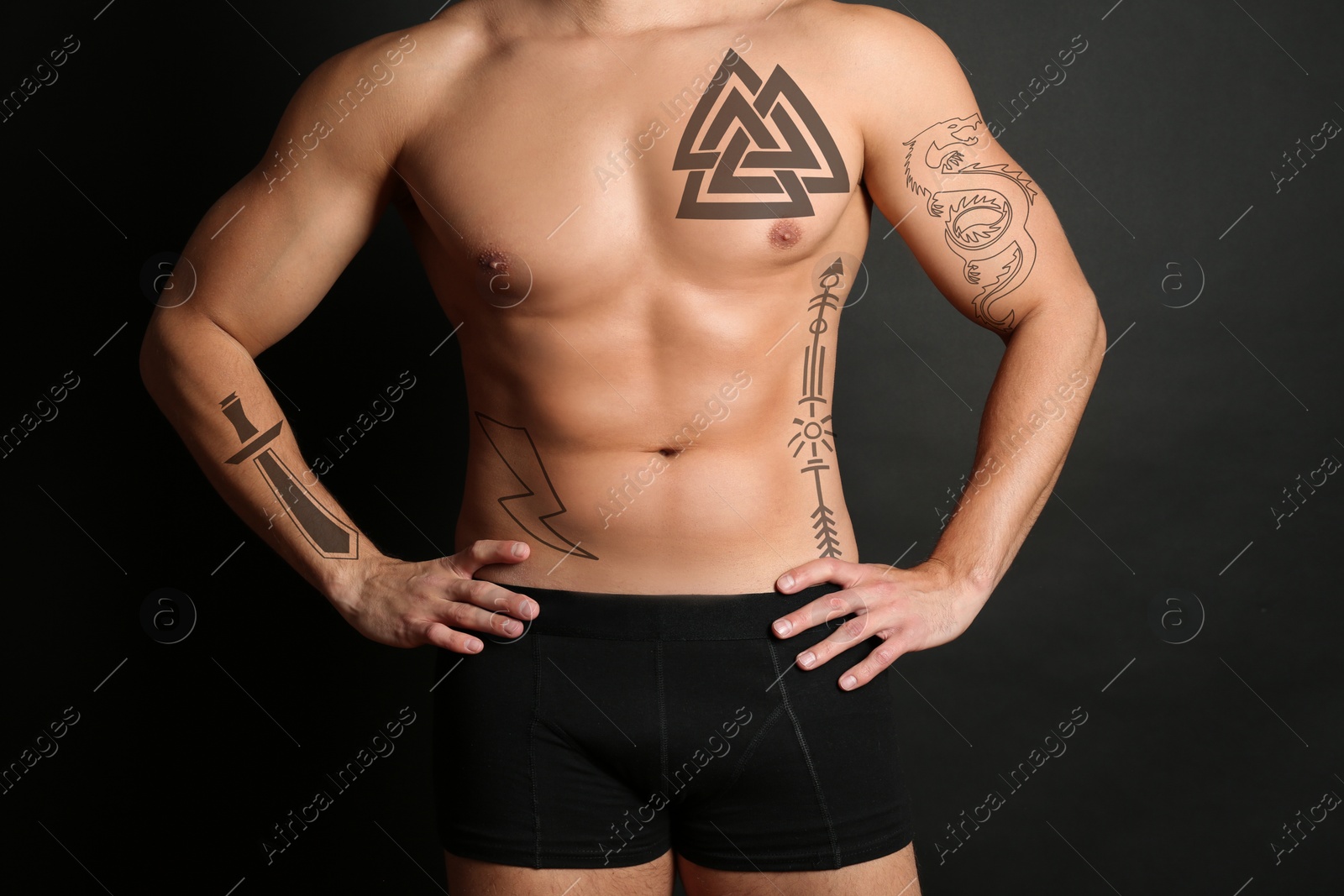 Image of Handsome man with beautiful tattoo sketches on black background, closeup